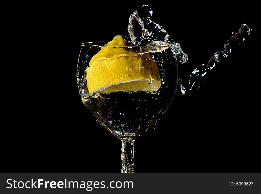 Piece of lemon falling in a glass making a big splash. Piece of lemon falling in a glass making a big splash