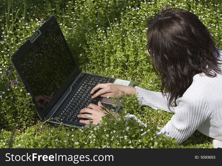 Woman laying down on grass with laptop. Woman laying down on grass with laptop