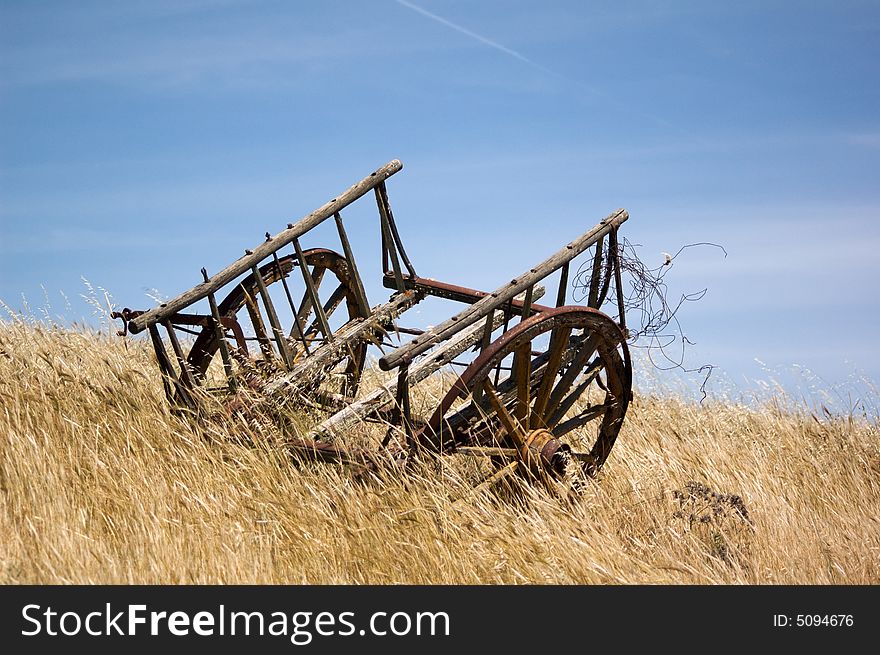 Ancient abandoned chariot in a field in a summer day's blue sky with light clouds