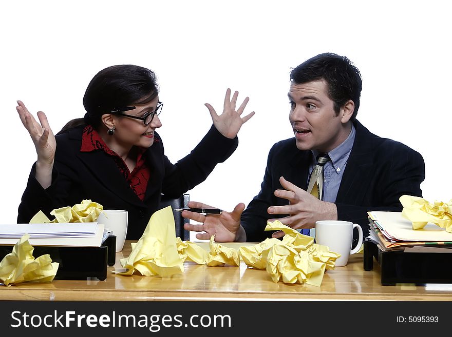 An isolated shot of a businessman and businesswoman discussing ideas at a desk, littered with yellow paper. An isolated shot of a businessman and businesswoman discussing ideas at a desk, littered with yellow paper.