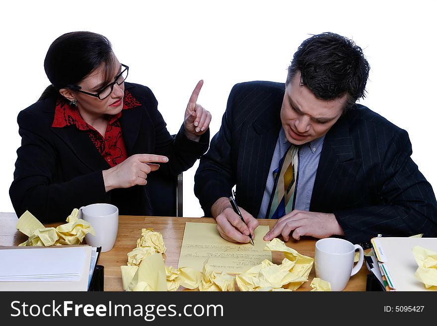 An isolated shot of a businessman and businesswoman writing notes at a desk, littered with yellow paper. An isolated shot of a businessman and businesswoman writing notes at a desk, littered with yellow paper.