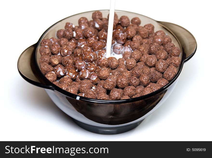 Chocolate cereal with milk in a glass bowl on white background