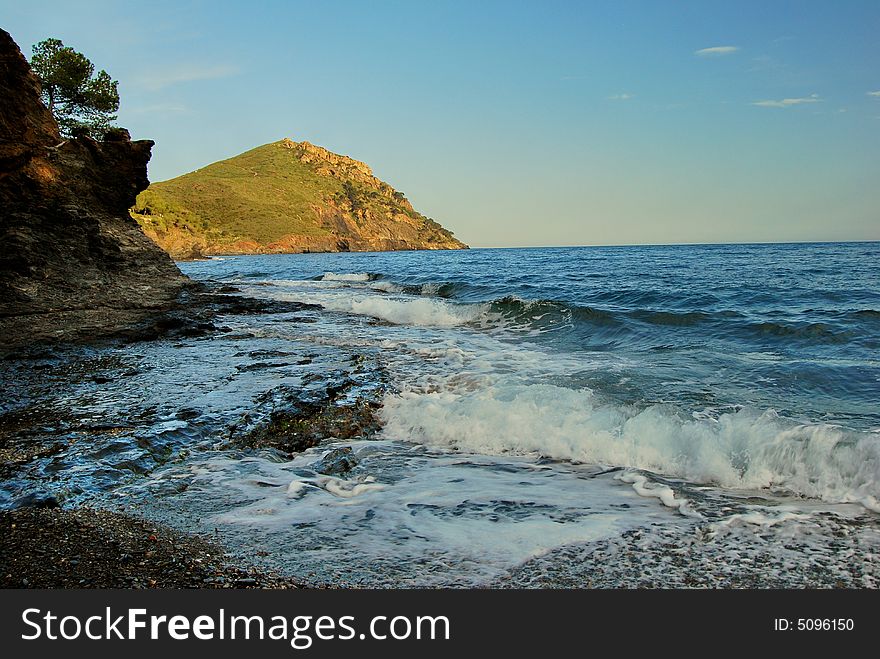 View on a headland and the bay in the sunset light. The Mediterranean Sea, the Costa Brava region. View on a headland and the bay in the sunset light. The Mediterranean Sea, the Costa Brava region.