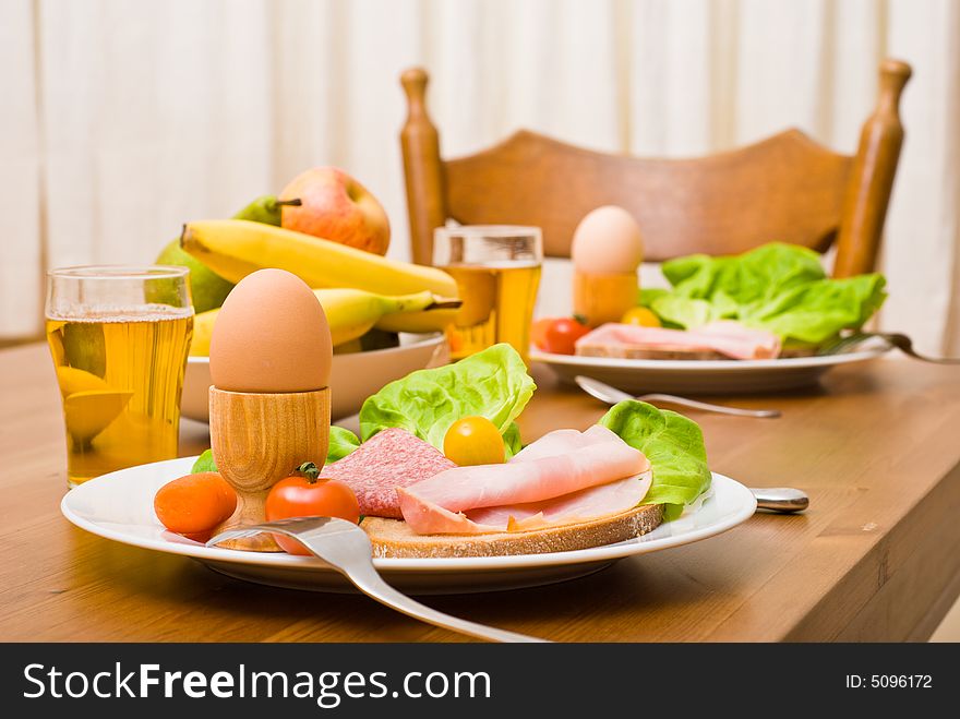 Table served with snacks. Fruits, vegetables, bread, egg, ham etc. Focus on the front egg, shallow depth of field. Table served with snacks. Fruits, vegetables, bread, egg, ham etc. Focus on the front egg, shallow depth of field.