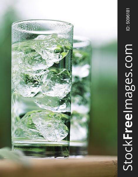 Sparkling water with icecubes in front of a garden background. Sparkling water with icecubes in front of a garden background