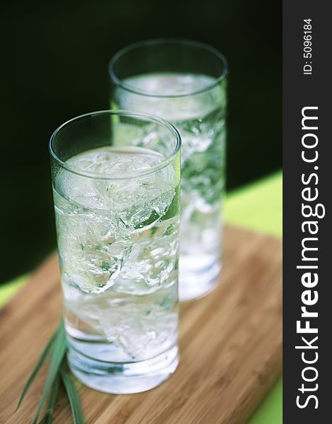 Sparkling water with icecubes in front of a garden background. Sparkling water with icecubes in front of a garden background