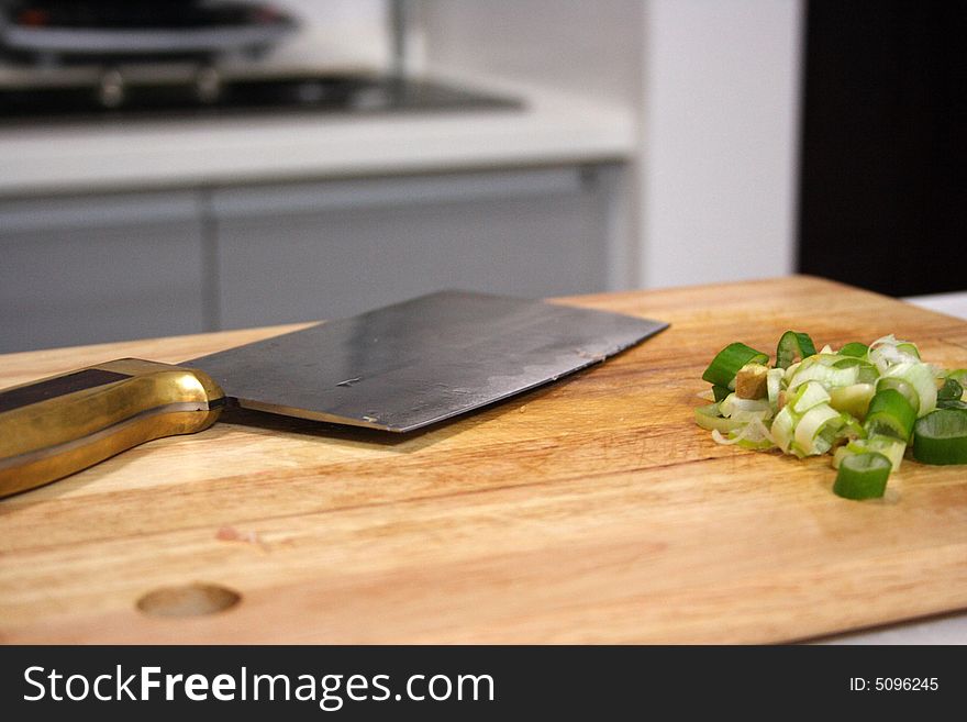 A kitchen knife and shallot on the board. A kitchen knife and shallot on the board