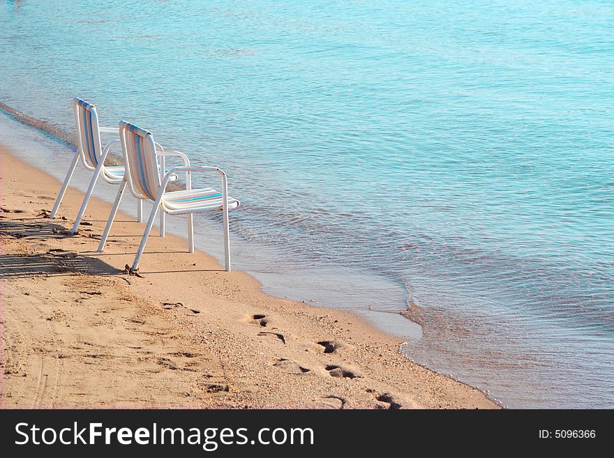 Two empty beach chairs on a lonely quite beach early in the morning. The location is at Hurghada, Egypt. Two empty beach chairs on a lonely quite beach early in the morning. The location is at Hurghada, Egypt.