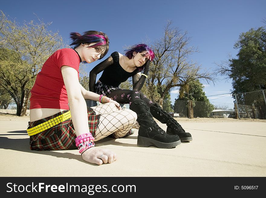 Two Punk Girls Sitting on a cement playground