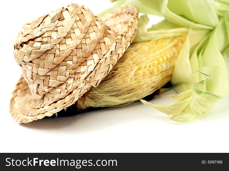 Straw hat and fresh ear of corn over a white background. Straw hat and fresh ear of corn over a white background