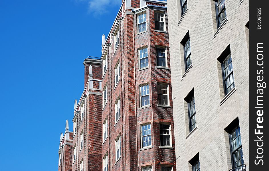 Urban brick apartment buildings from below with blue sky