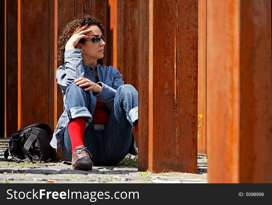 Young woman waits to somebody between rusty columns