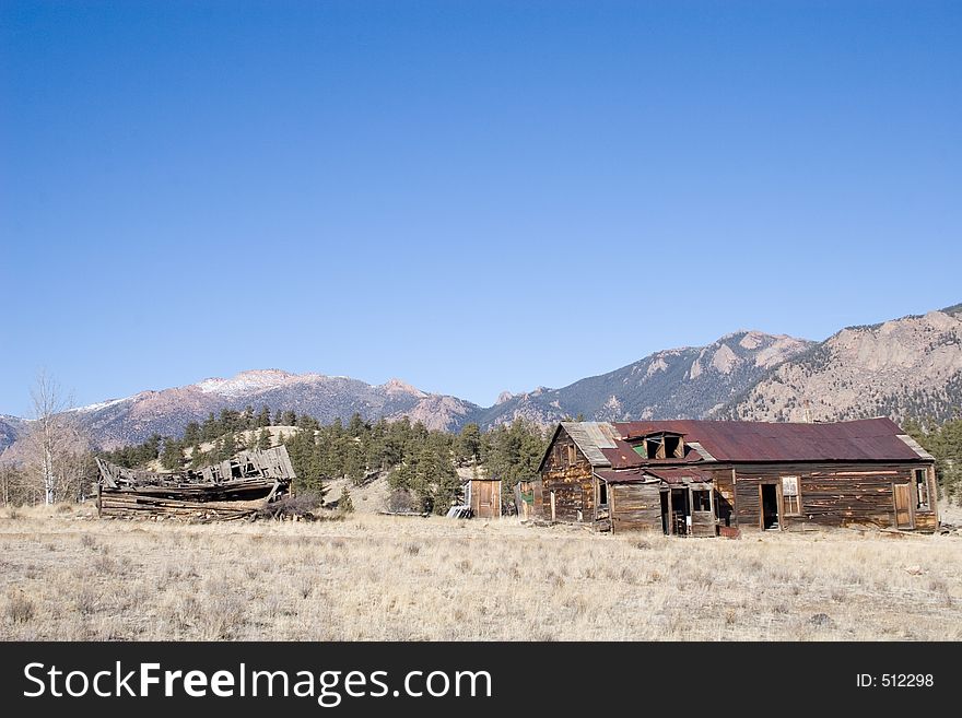 An old, abandoned and falling mining/ranch boardinghouse in Tarryall, Colorado, with the Rocky Mountains in the background. An old, abandoned and falling mining/ranch boardinghouse in Tarryall, Colorado, with the Rocky Mountains in the background.