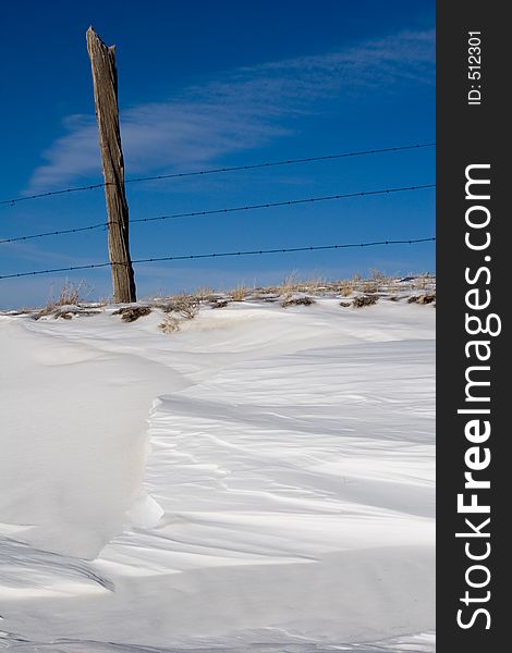 Barbed wire fence, fencepost and drifts of snow mark the beginning of winter in the South Park area of central Colorado. Barbed wire fence, fencepost and drifts of snow mark the beginning of winter in the South Park area of central Colorado.