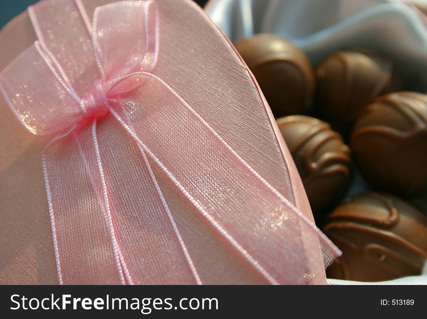 Pink gift box lid with chocolates in the background. Pink gift box lid with chocolates in the background.