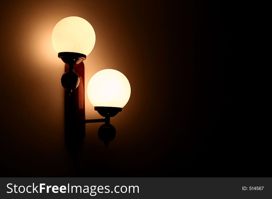 View of lightened double lamp on a shadowed wall