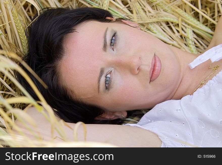 Natural beautiful girl in the field of golden wheat laying and dreaming