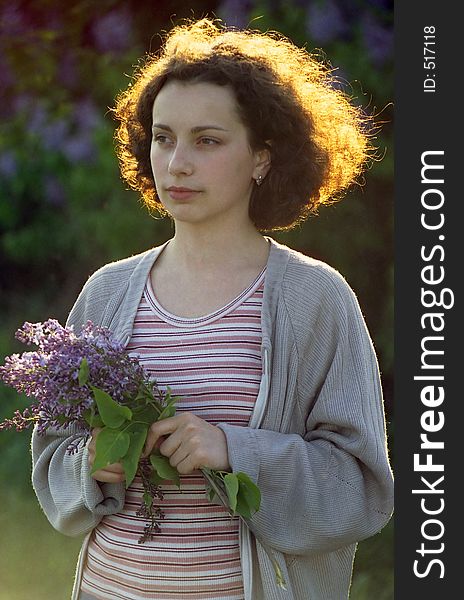 Evening portrait of a girl with the lilac bouquet