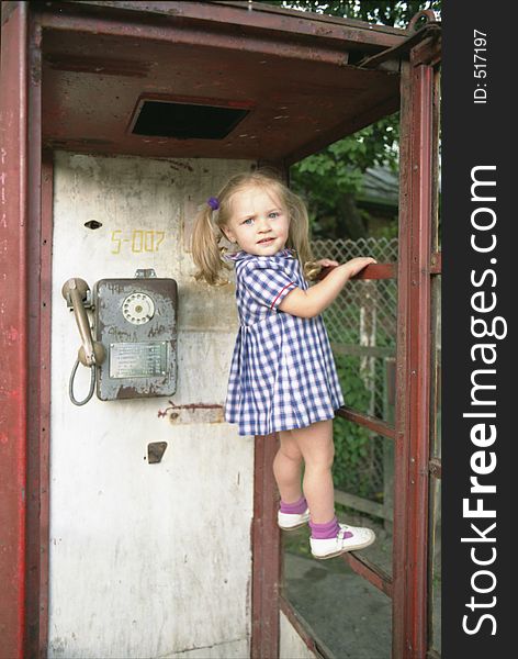 Portrait of the pretty girl standing on the horizontal bar in the phone booth. Portrait of the pretty girl standing on the horizontal bar in the phone booth