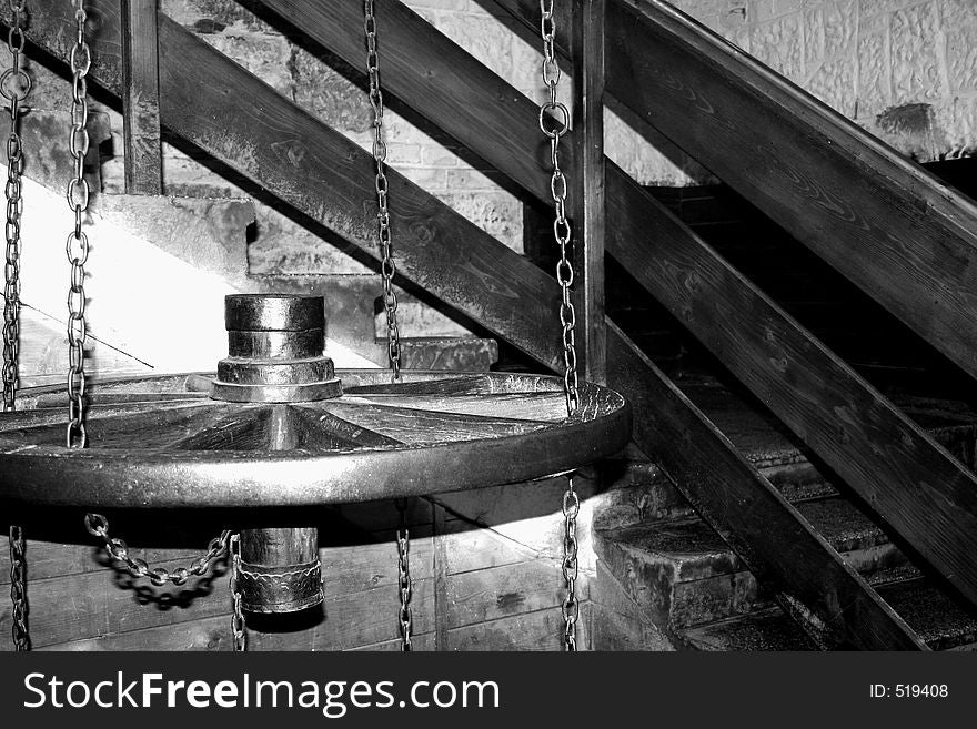 A wagon wheel hung by some chains in a staircase