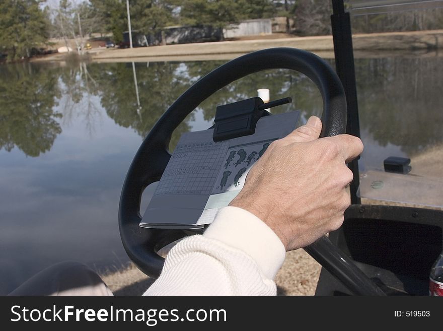 Driving golf cart to the next hole with score card visible. Driving golf cart to the next hole with score card visible.