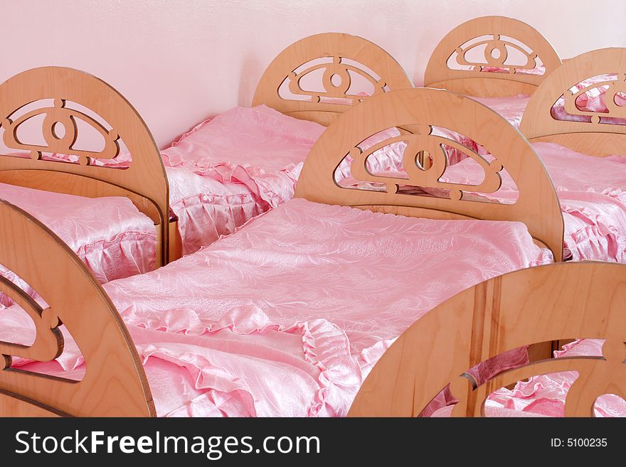 Interior with small beds in rows, pink coverlets and wall. Interior with small beds in rows, pink coverlets and wall