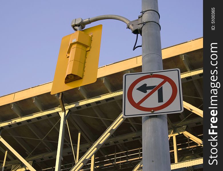 A sign indicates No Left Turn allowed near a bridge and traffic light.