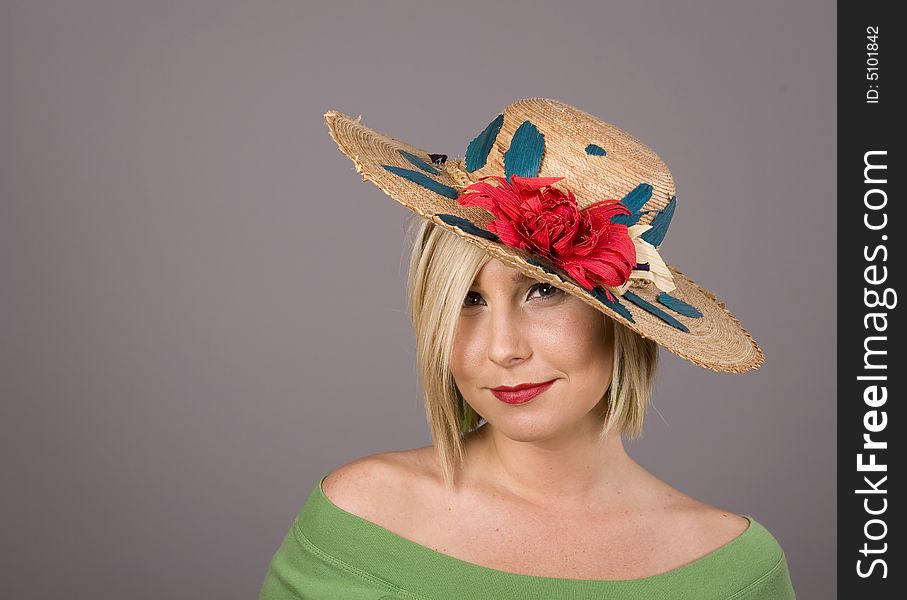 A blonde wearing a flowered straw hat with an odd look on her face. A blonde wearing a flowered straw hat with an odd look on her face.