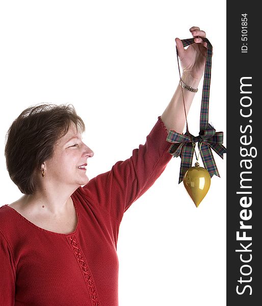 An attractive middle-aged woman in red holding up a gold Christmas ornament on green plaid ribbon. An attractive middle-aged woman in red holding up a gold Christmas ornament on green plaid ribbon