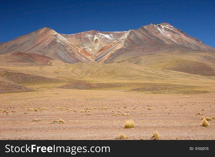 Feature land with beautiful geological feature in background. Vulcano. Altiplano. Bolivia