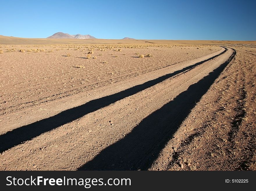 Azure clear sky over the dirt road leading to mountain range. Altiplano. Bolivia. Azure clear sky over the dirt road leading to mountain range. Altiplano. Bolivia
