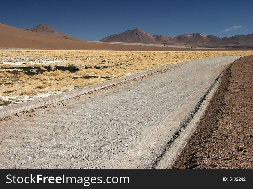 Road leading cross mountain range full of grass growing on rocky grounds. Altiplano. Bolivia. Road leading cross mountain range full of grass growing on rocky grounds. Altiplano. Bolivia.