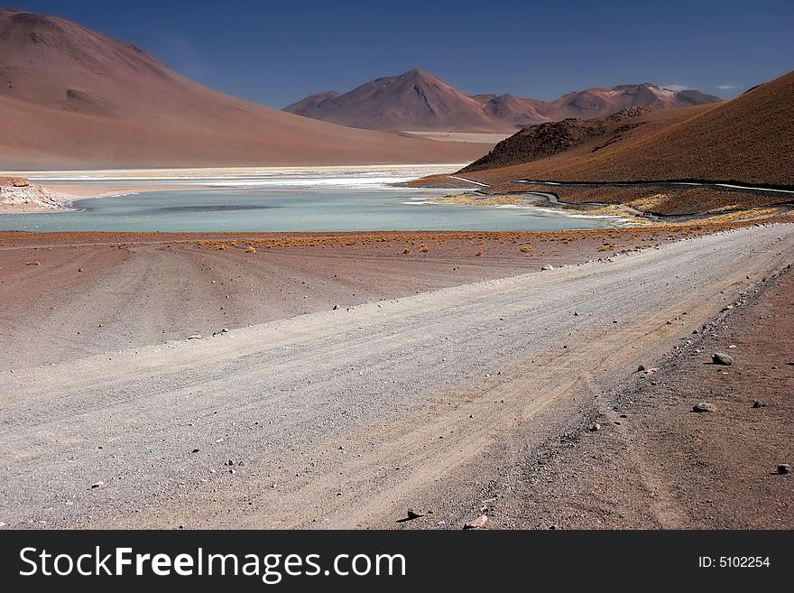 Azure clear sky over the mountain range with lake and country road leading cross mountains. Altiplano. Bolivia. Bolivia-Chilean border. Azure clear sky over the mountain range with lake and country road leading cross mountains. Altiplano. Bolivia. Bolivia-Chilean border