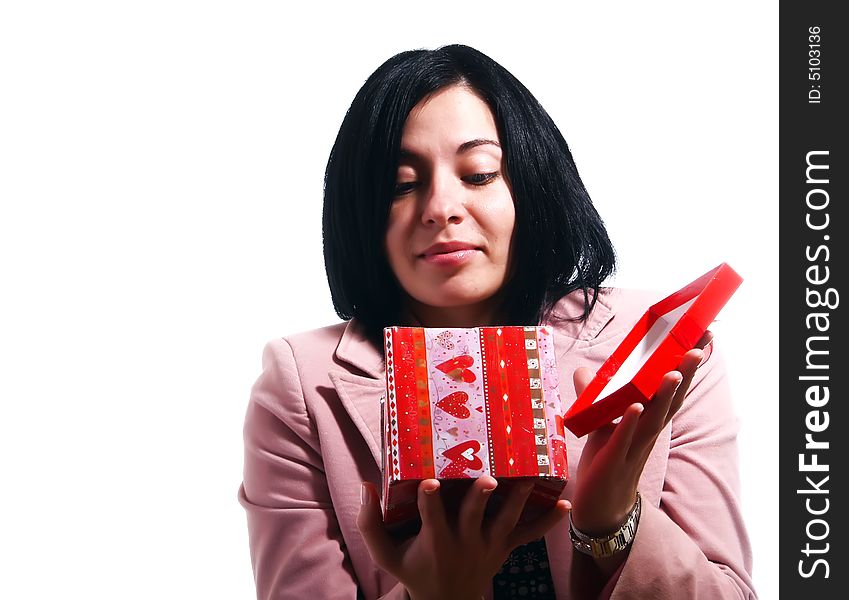 A portrait about a pretty trendy woman with black hair who is smiling, she is opening a gift what she got and she is excited. She is wearing a nice dress and a pink stylish coat. A portrait about a pretty trendy woman with black hair who is smiling, she is opening a gift what she got and she is excited. She is wearing a nice dress and a pink stylish coat.