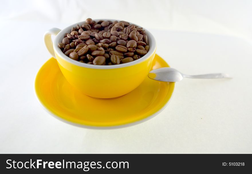 Yellow cup of coffee seeds