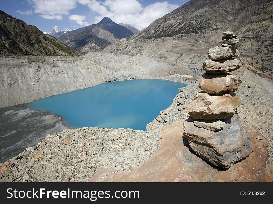 Memorial stones piled in front of blue mountain lake, annapurna, nepal