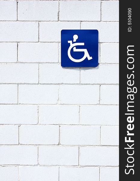Blue handicap symbol at white wall. Blue handicap symbol at white wall