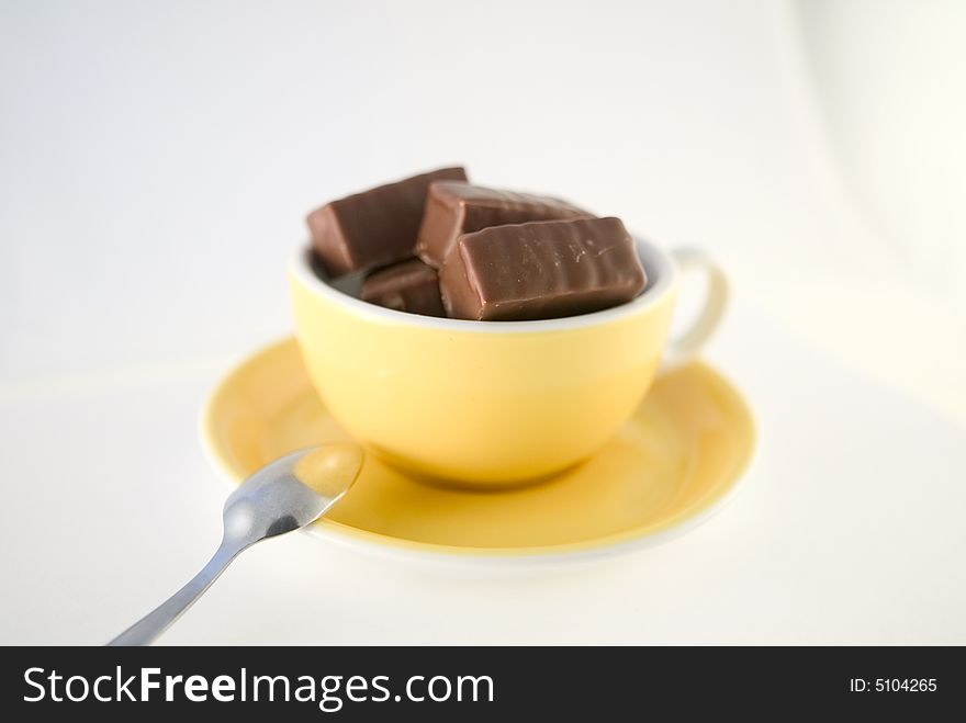 Chocolate candies in yellow cup, hot chocolate