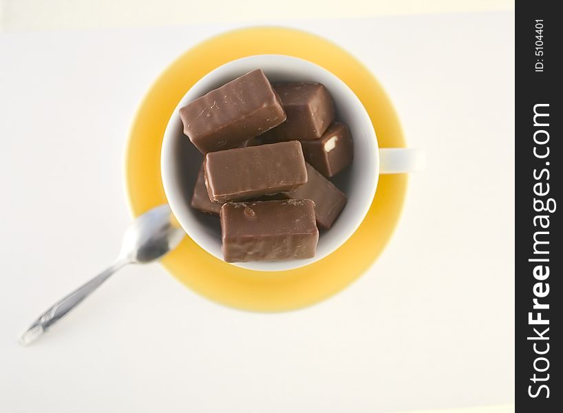 Chocolate candies in yellow cup, hot chocolate
