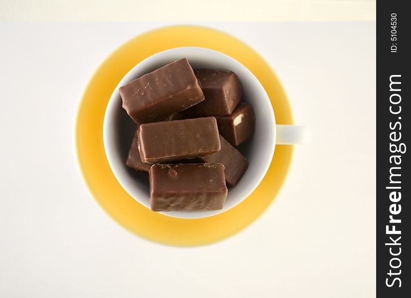 Chocolate candies in yellow cup, hot chocolate