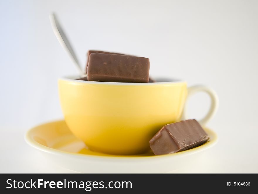 Chocolade candies in yellow cup, hot chocolate