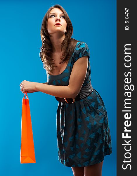Beautiful Fashion Model with shopping bag over blue background