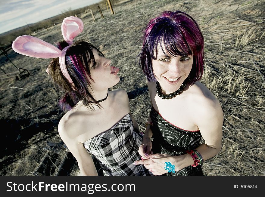 Punk girl sticking her tongue out at her friend. Punk girl sticking her tongue out at her friend