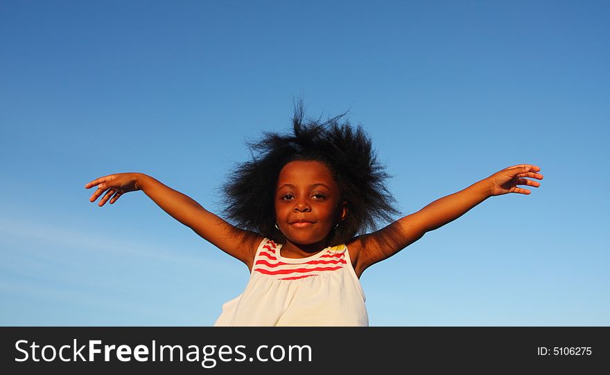 Young girl waving her arms with blue sky background. Young girl waving her arms with blue sky background.
