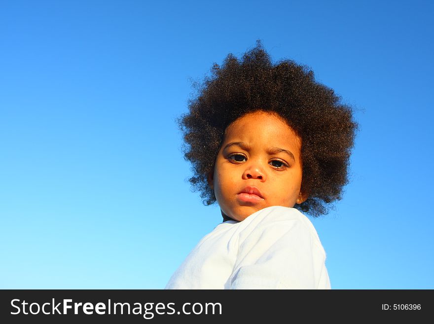 Cute little child with a blue sky background. Cute little child with a blue sky background.