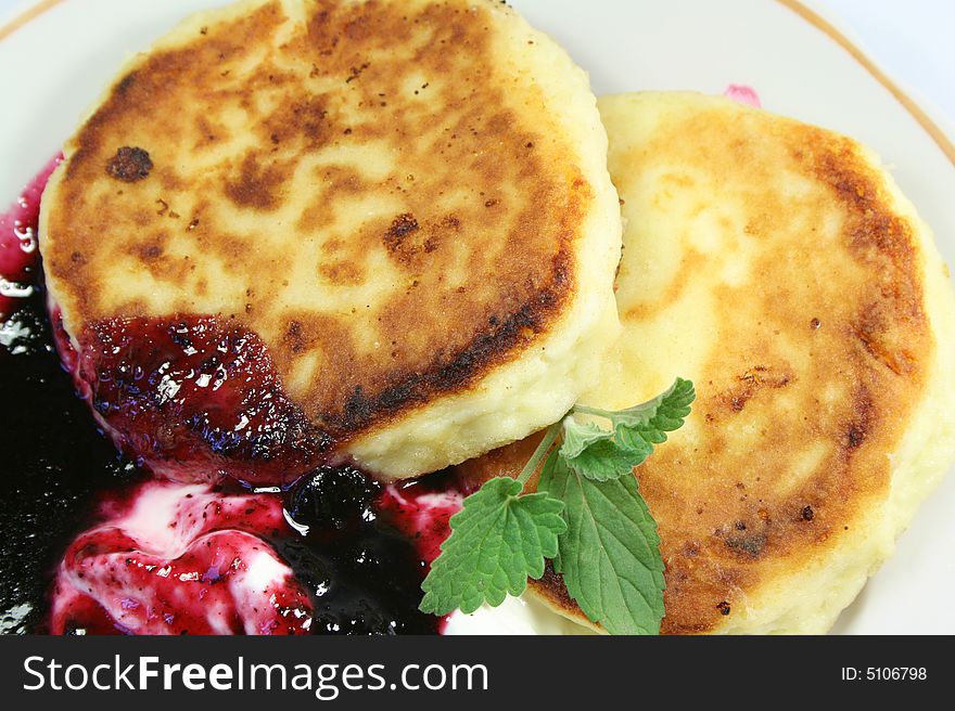 Pancakes from cottage cheese with jam, sour cream and leaves of mint.