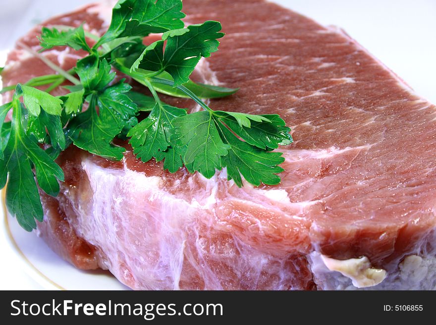 Piece of crude meat with leaves of a parsley