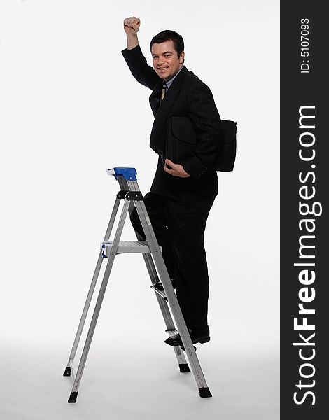 Businessman smiling as he climbs up a stepladder, briefcase in hand while pumping his fist in the air. Isolated against a white background. Businessman smiling as he climbs up a stepladder, briefcase in hand while pumping his fist in the air. Isolated against a white background
