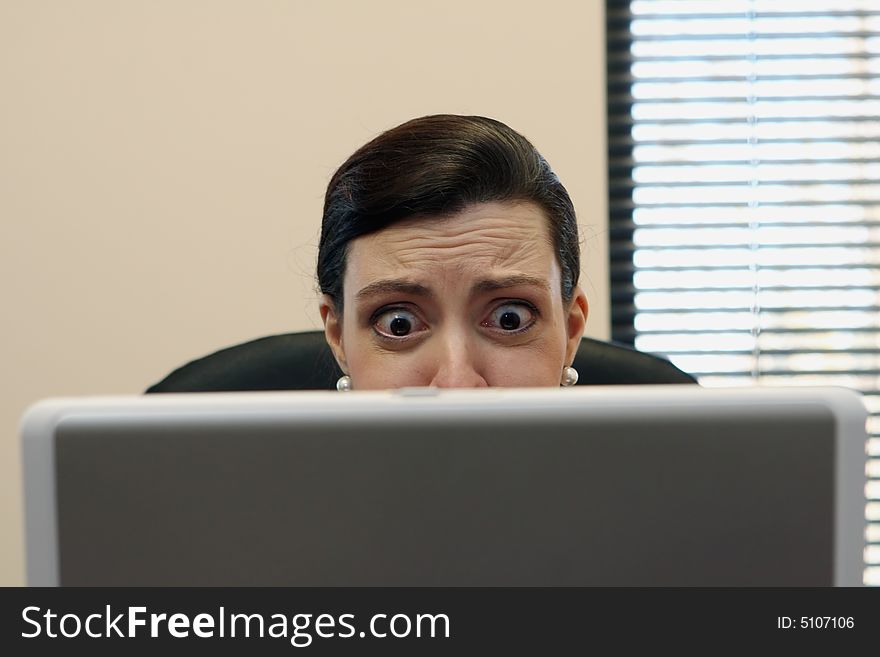 Businesswoman sitting at her desk behind her laptop screen. Businesswoman sitting at her desk behind her laptop screen