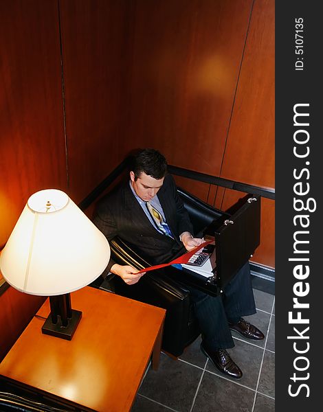 Businessman waiting in an office lobby with his briefcase open. Businessman waiting in an office lobby with his briefcase open